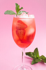 Cocktail drink with strawberry and ice in a glass on the pink  background. Location vertical. Closeup.