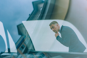 Businessman in a blue jacket on the background of the car.