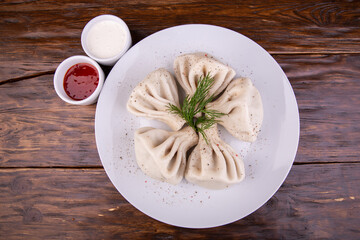 Boiled khinkali seasoned with pepper with sour cream and ketchup