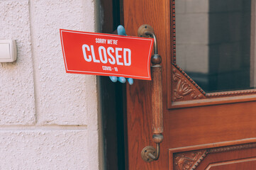 Guy shows a sign Sorry We're Closed COVID-19 about door.