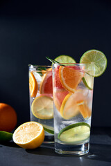 Health care, fitness, healthy nutrition diet concept. Fresh cool homemade citrus infused detox water with grapefruit, orange, lemon and lime and ice in glasses on dark background.