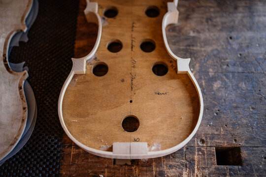 High angle of wooden soundboard with round holes and attached shells on workbench in workshop