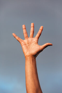 Hand of anonymous black woman against a blue sky