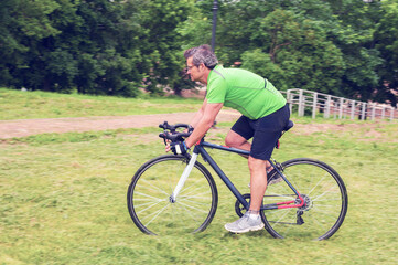 Fototapeta premium Riding adult cyclist on his road bicycle in a park