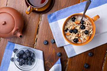 breakfasr with oatmeal porridge with blueberries, fruits,  almonds and coconut milk. Healthy and tasty vegan breakfast. top view, flat lay.