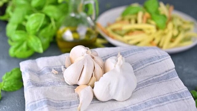 Head of garlic on a napkin. Ingredient for traditional italian pesto sauce. Healthy foods, vitamins and benefits. Together with pasta and basil on the table