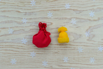 Christmas layout with red gift bag and small knitted winter hat on a wooden background.