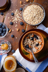 breakfasr with oatmeal porridge with blueberries, fruits,  almonds and coconut milk. Healthy and tasty vegan breakfast. top view, flat lay.