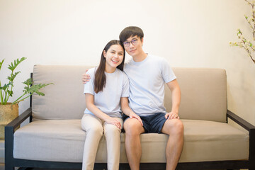 Fototapeta na wymiar a happy couple wearing blue shirt is sitting on a sofa at home