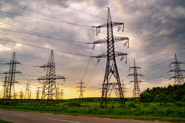 Electricity pylons and high-voltage power lines on the green grass. Power plant. Electrical power grid. View from below.