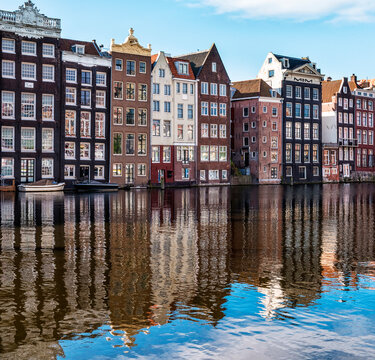 Traditional buildings along the Damrak reflected in the canal, Amsterdam, the Netherlands