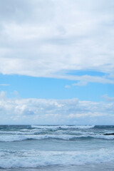 Fototapeta na wymiar Mar con olas y cielo con nubes vertical
