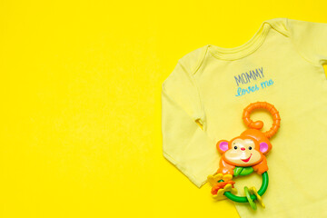 children's clothing and baby accessories on a yellow background top view with space for text