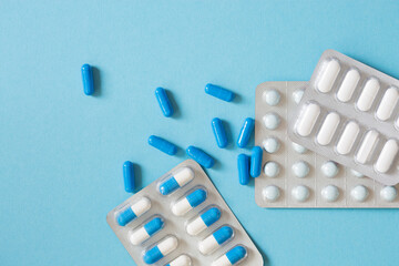 Different types of medication, tablets, capsules on blue background.