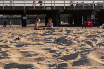 Santa Cruz, California / USA - June 18 2018: Two blurred little boys playing with sand on Santa Cruz Boardwalk Beach. Space for text