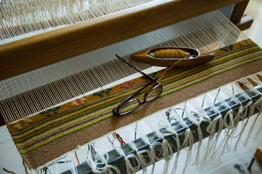 High angle view of eyeglasses and needle on handloom weaving machine