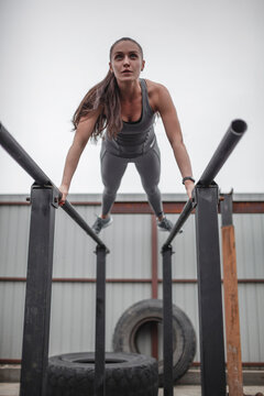 Low angle view of female athlete doing push-ups on parallel bars during crossfit training