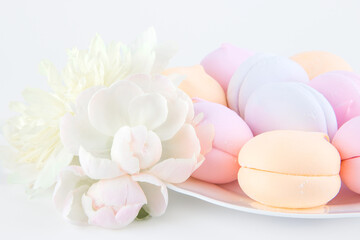 colorful marshmallows and cookies on a plate with peony flowers, isolate on a white background