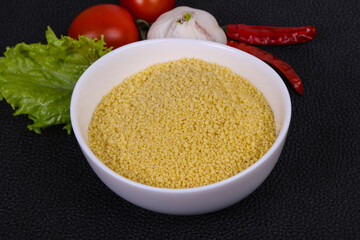 Raw couscous in the bowl served salad leaves, tomato and pepper