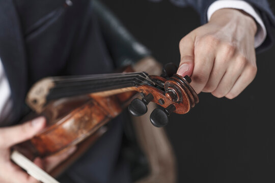 Cropped image of musician tuning violin strings