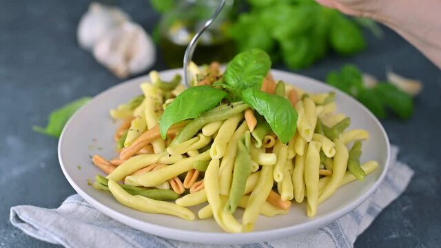 Homemade apulian pasta of different colors cooked with basil, garlic, olive oil. Typical dish of Southern Italy of Puglia, Salento. Orecchiette and Maccheroni.Hand with a fork in the frame.  4k video