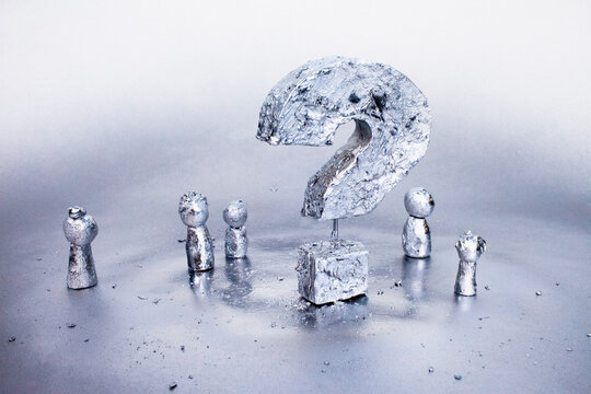 Close-up of silver question mark against gray background