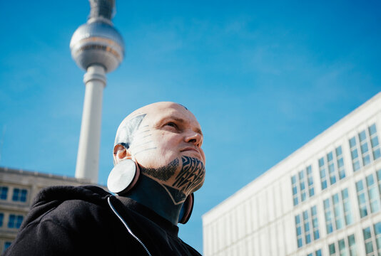 Low angle view of man with tattoos and earplug earring standing outdoors