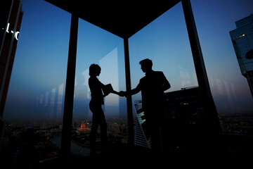 Silhouette of businessman shaking hands in honor of the transaction with his new woman partner,...