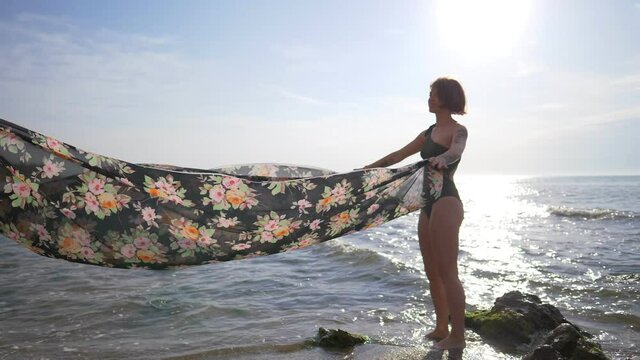 two young women at the beach enjoying themselves, waving a pareo in the wind at sunrise, vacations, holiday carefree concept