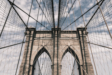 Low angle view of Brooklyn Bridge against cloudy sky