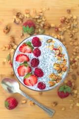 Chia pudding with raspberry chia jam in a glass garnished with strawberries, raspberries and granola. Healthy breakfast concept