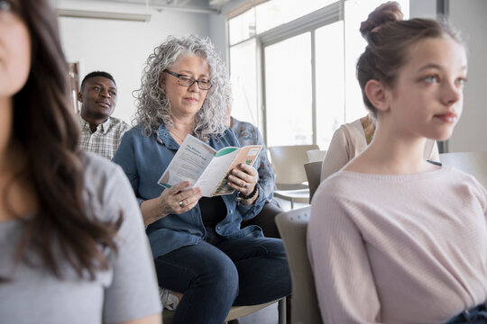 Woman reading environmental brochure in conference audience
