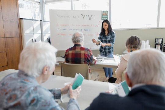Young woman teaching nutrition class to seniors in community center