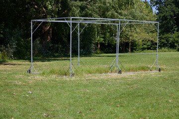 Cricket cage without net in field with trees in background