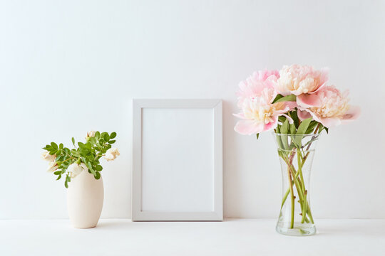 Mockup with a white frame and pink peonies in a vase on a white background