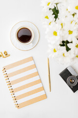 Naklejka premium Flat lay blogger or freelancer workspace with a notebook, white flowers, a cup of coffee on a white background