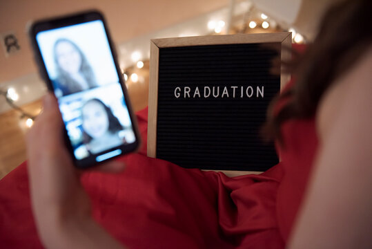 Close up teenage girl with graduation sign video chatting with friends