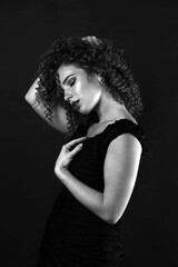 Fototapeta premium Black and white portrait of a cute curly girl in a black dress