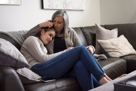 Affectionate Mother Comforting Teenage Daughter On Living Room Sofa