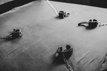 BDSM Leather handcuffs for role-playing games on a gray sheet. Bondage for carnal pleasures....