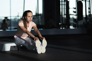 Woman doing stretching exercises for her legs at the gym