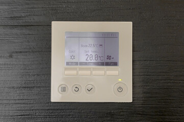 Air conditioning control panel. Digital thermostat on black wooden wall. Thermostat digital programmable.