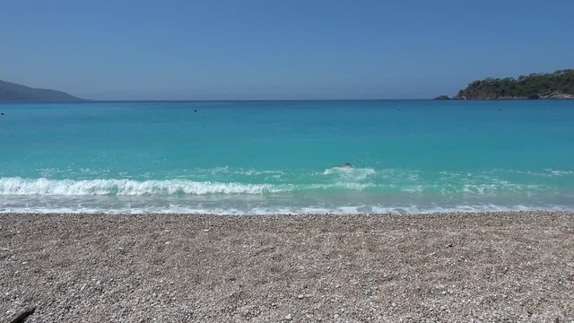 Oludeniz, Fethiye, Turkey - 11th of June 2020: 4K First post quarantine holiday - Slim man runs in the blue sea waters and swims away
