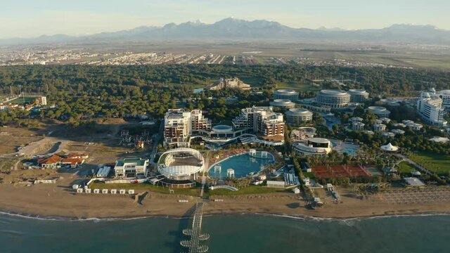 Big area of a luxury resort along beautiful sea shore. Mountains in the background. Drone footage 4K