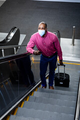 Fototapeta na wymiar African American wearing covid19 coronavirus mask standing on escalator