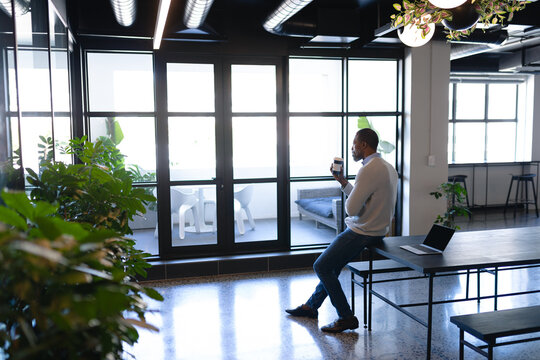 African American man looking outside and drinking coffee