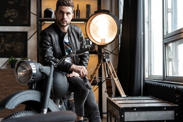 Fototapeta na wymiar Stylish young man in leather jacket sitting on motorbike.