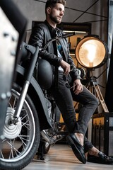 Fototapeta na wymiar Stylish young man in leather jacket sitting on motorbike.