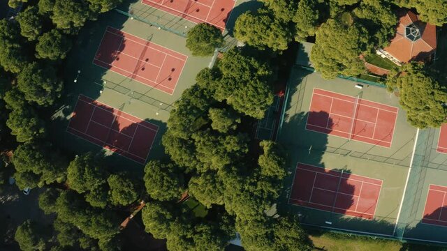 Birds Eye Aerial View of Tennis Courts between green trees in summer time.
