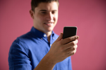 Caucasian man using a smartphone on pink background
